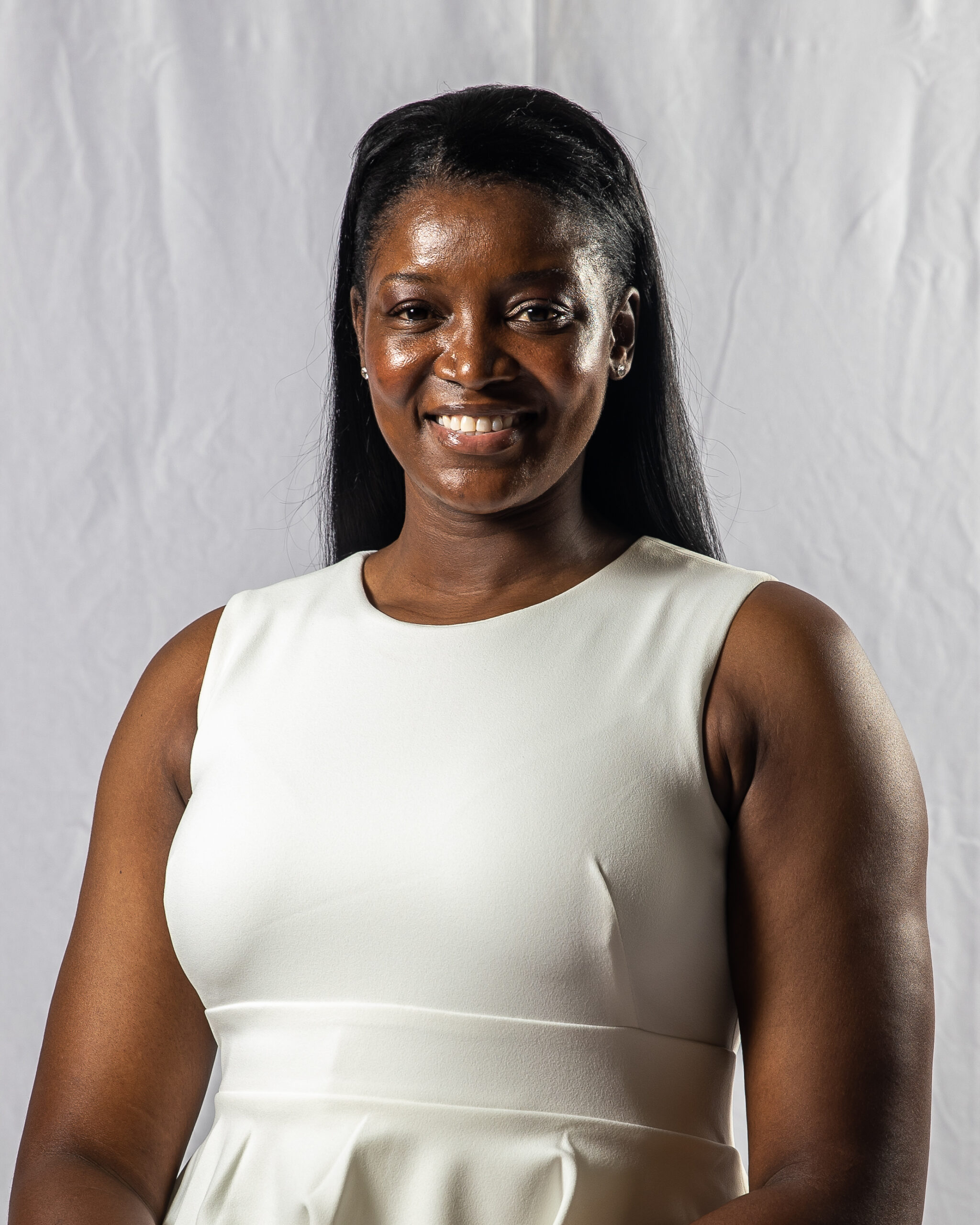 A woman in a white dress smiling for the camera.