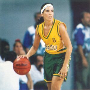 A woman in a green and yellow uniform holding a basketball, showcasing the history of women's basketball.