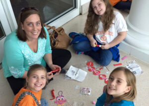 A group of girls sitting on the floor making crafts.
