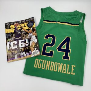 A green jersey showcasing the rich history of women's basketball with a magazine nearby.