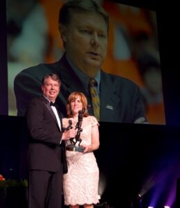 A man and woman standing on stage holding an award.