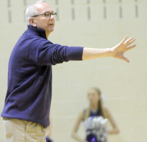 A man in glasses is pointing to his team during a basketball game, highlighting their remarkable teamwork and skills.