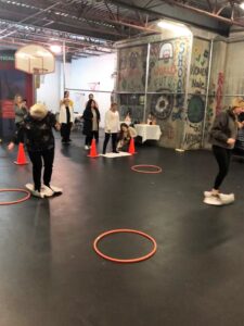 A group of people playing hula hoops in a gym.