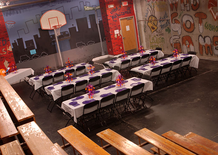 Tables are set up in a basketball court, creating a versatile space for Hall of Fame or youth events.