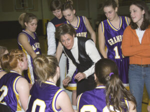 A basketball coach discussing the history of women's basketball with a group of girls.