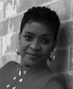 Black and white photo of a woman leaning against a brick wall.