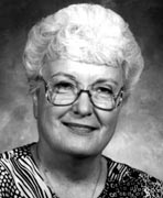 A black and white photo of an older woman wearing glasses.