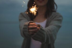 A woman holding a sparkler in her hand.