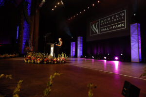 A woman receiving the prestigious Berenson Trophy, standing confidently at a podium.