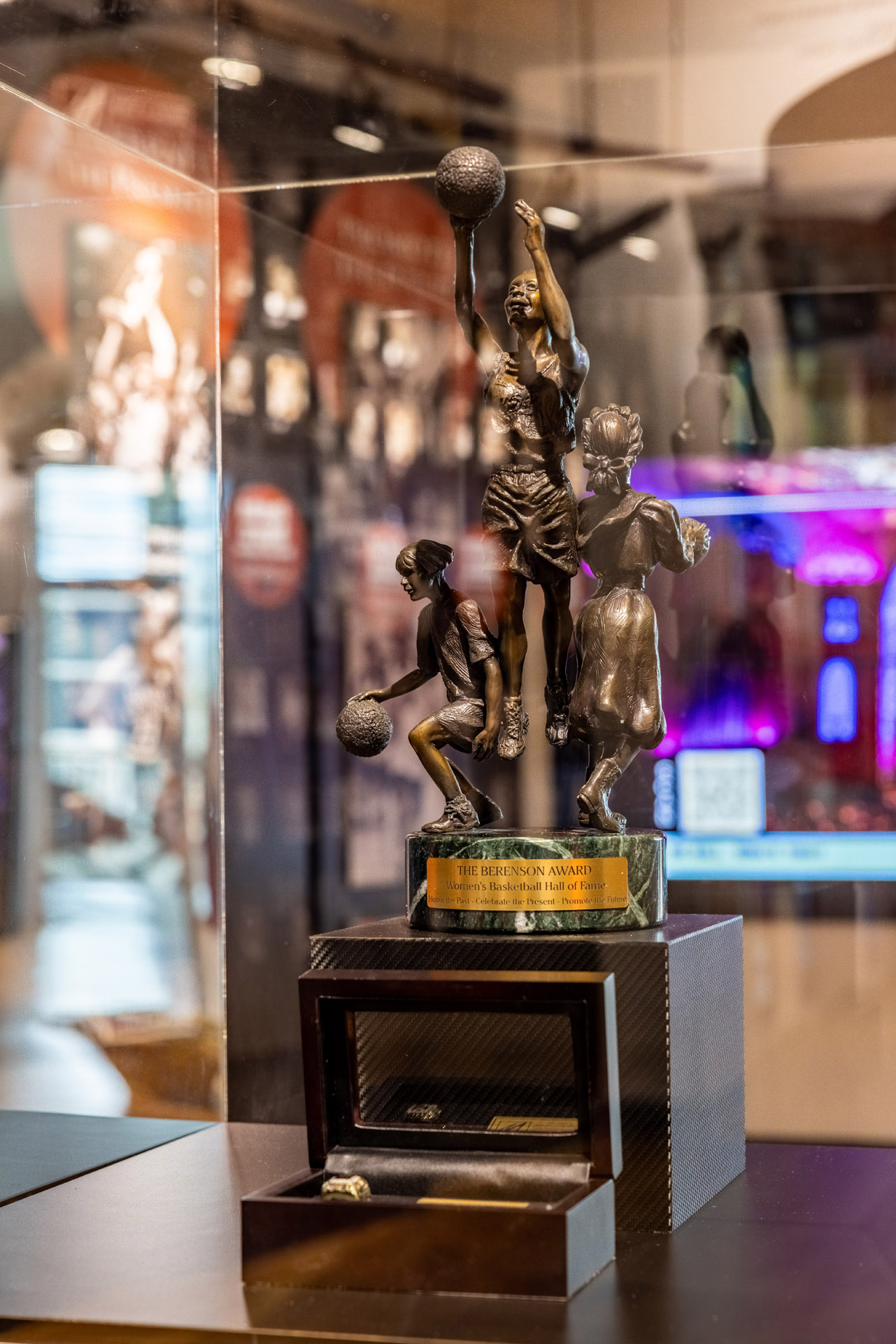 A berenson trophy statue of a basketball player is on display in a glass case.