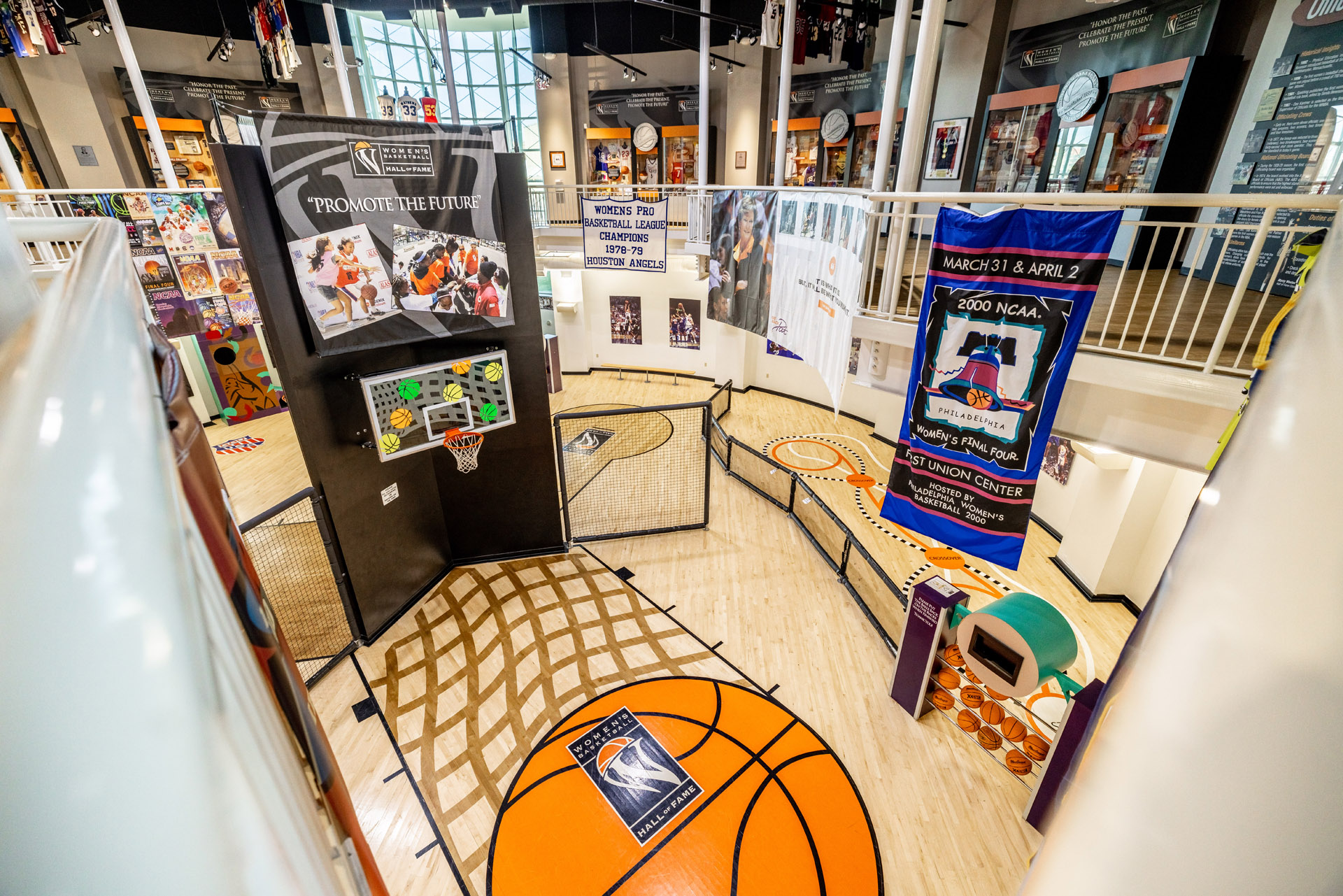 A basketball court in a museum showcasing Hall of Fame posters and banners for youth events.